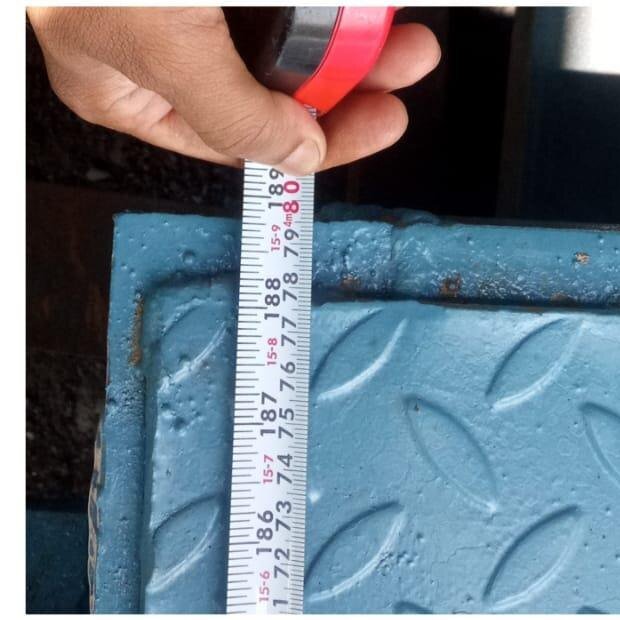 Technician measuring a fabricated member with a tape for dimensional check